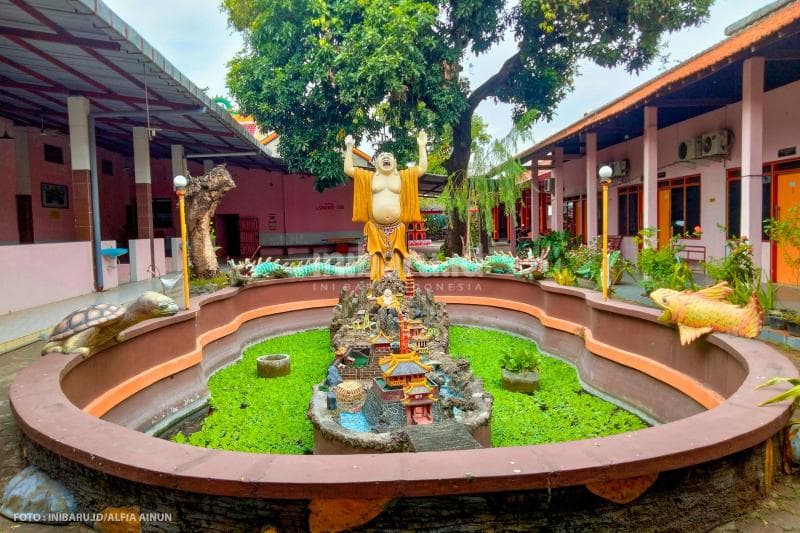 Maitreya atau Buddha Tertawa diletakkan di tengah kolam.